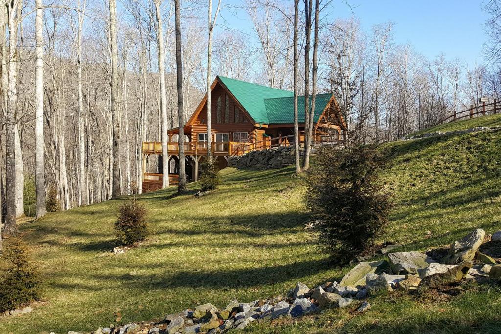 una cabaña de madera en una colina con techo verde en Tenderfoot Lodge, en Maggie Valley