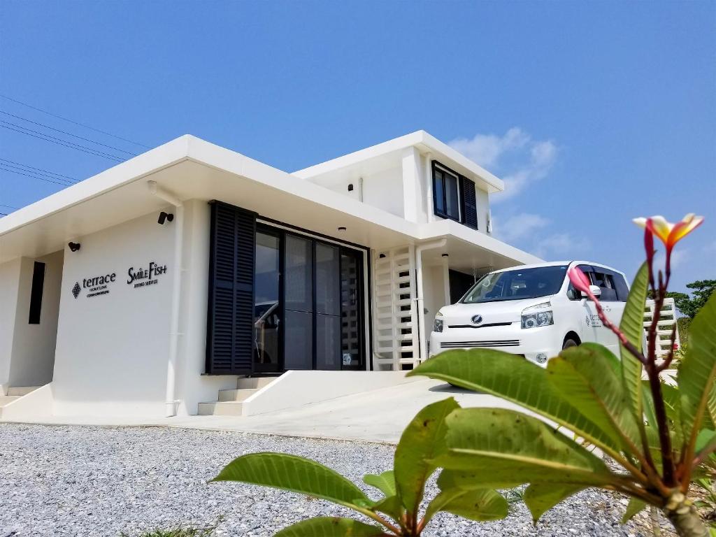 uma casa branca com um carro estacionado em frente dela em terrace IRIOMOTEJIMA CONDOMINIUM em Iriomote