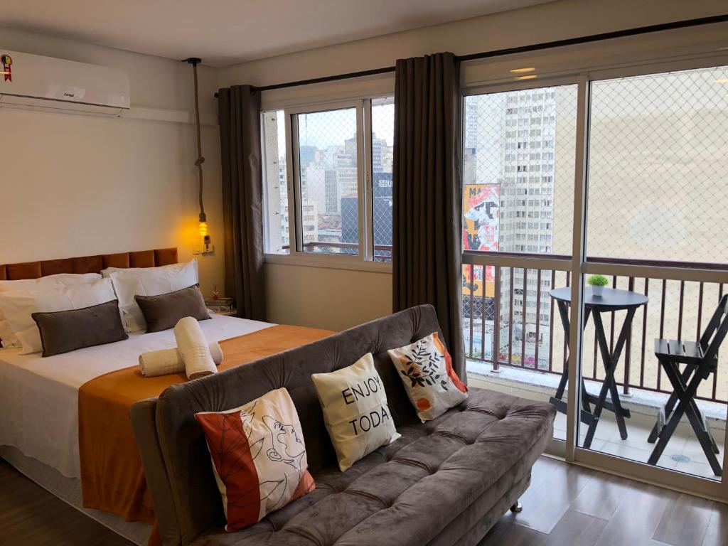 1 dormitorio con cama, sofá y balcón en SeuLar o conforto de um Lar em Qualquer Lugar en São Paulo