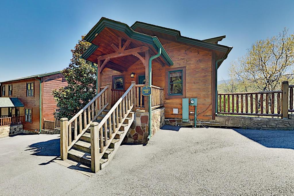 uma cabina de madeira com uma escada que conduz à porta da frente em Gatlinburg Falls Cabin Unit 812 em Gatlinburg