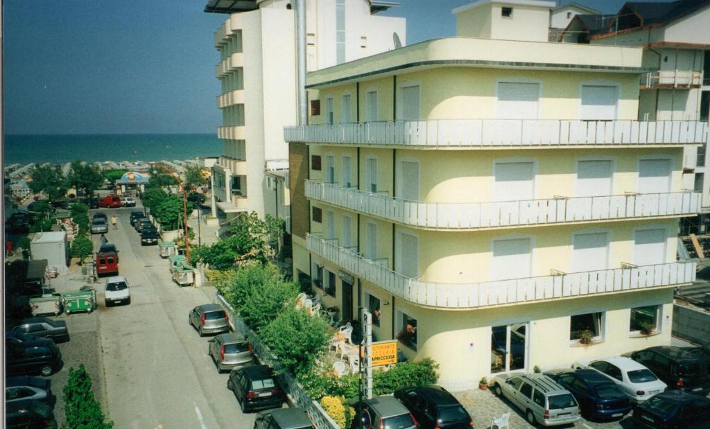 un edificio alto con coches estacionados al lado de una calle en Hotel Rivamare, en Cervia