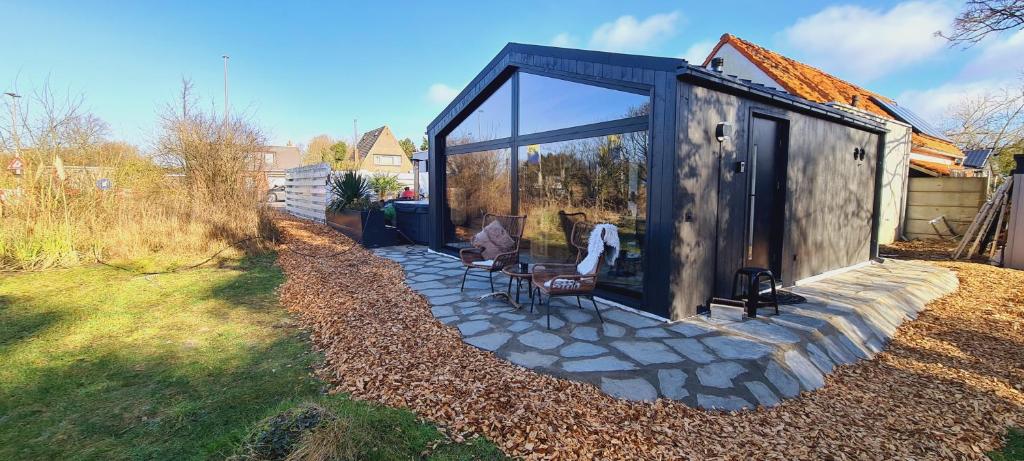 Cette petite cabine dispose d'une porte en verre et d'une terrasse en pierre. dans l'établissement B&B het duinhuisje met jacuzzi, gratis parkeren, 2 fietsen te leen, airco, à Zandvoort