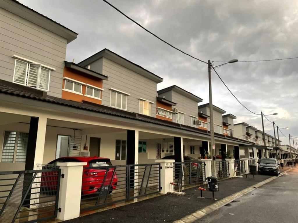 a row of houses with a red car parked in front at RS HOMESTAY BANDAR SERI ISKANDAR in Seri Iskandar