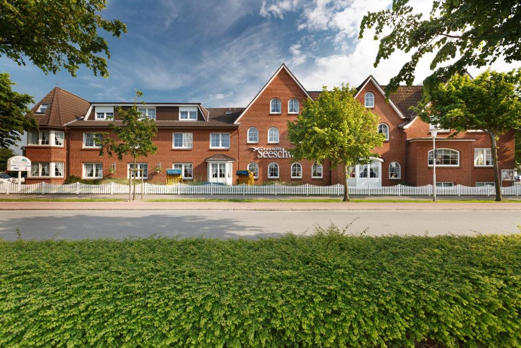 a large red brick building on a street at Hotel Seeschwalbe in Cuxhaven