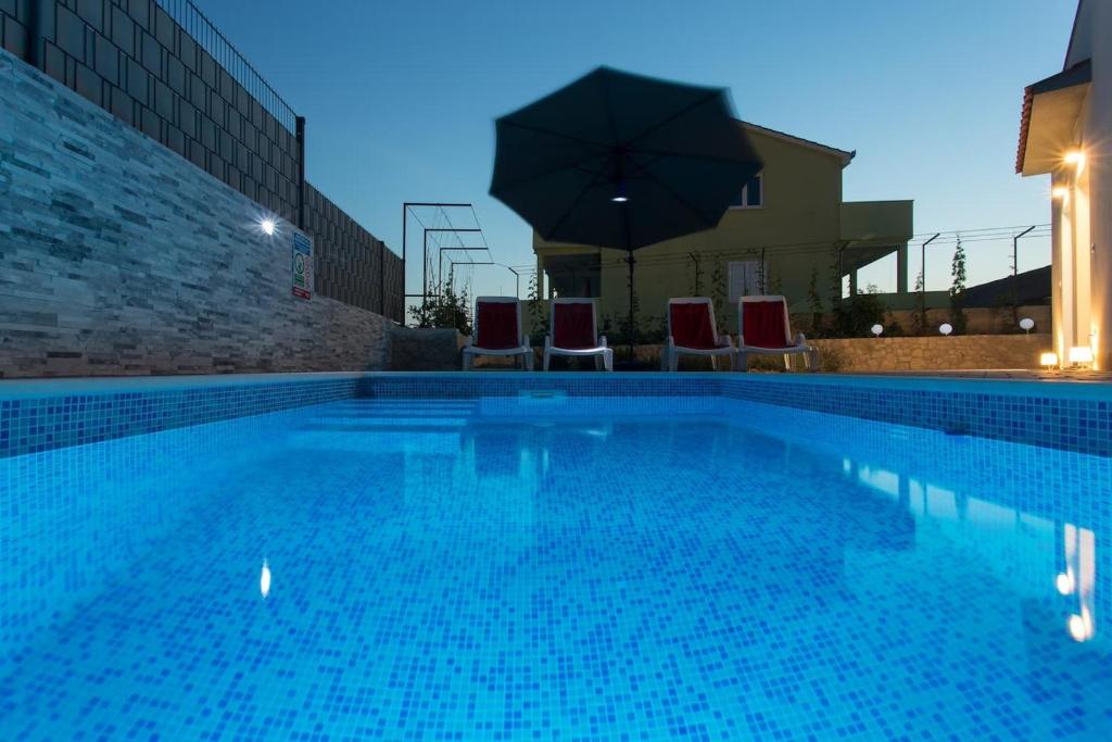 duży basen z krzesłami i parasolem w obiekcie Villa Ivica - with pool w mieście Vinišće