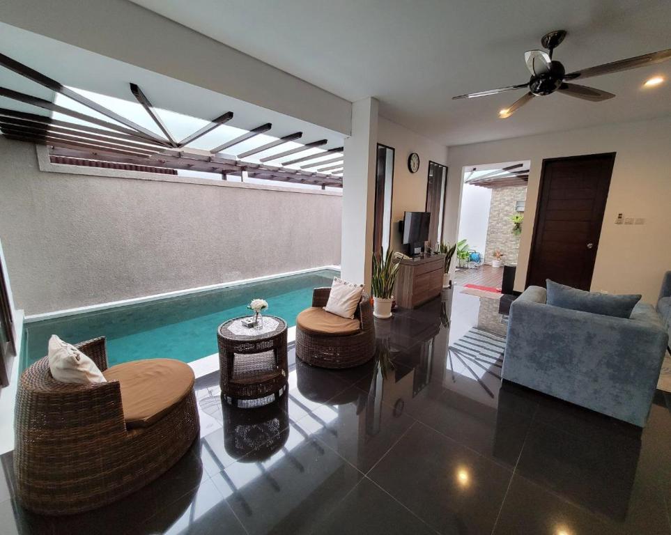 uma sala de estar com uma piscina e um sofá e cadeiras em B'da2ri Butiq Villa em Seminyak