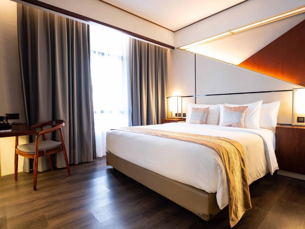 una camera d'albergo con un grande letto e una scrivania di Rayz UMM Hotel Malang a Malang