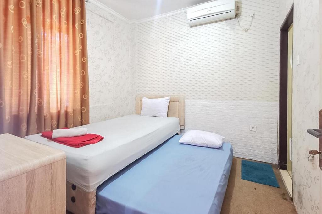two twin beds in a room with a window at Good Sleep Balikpapan Mitra RedDoorz in Balikpapan