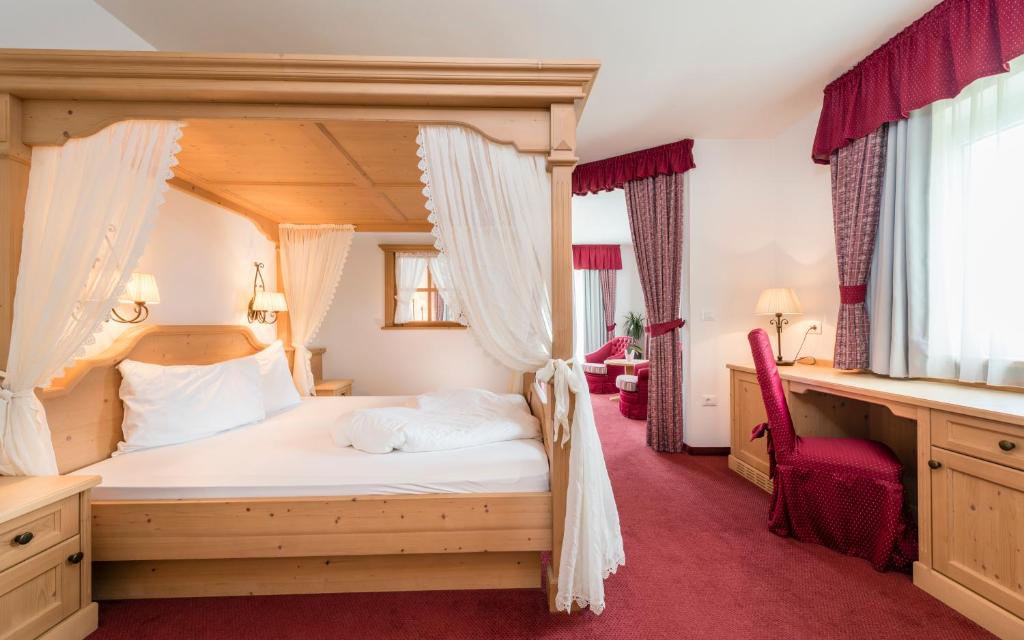 ein Schlafzimmer mit einem Himmelbett und einem roten Teppich in der Unterkunft Residenze Mathilda in Schlanders