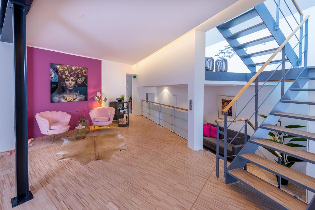 ギュータースローにあるLuxus Wellness Loft - 245qm - Designwohnen im Zentrumのピンクの壁と階段のあるリビングルーム