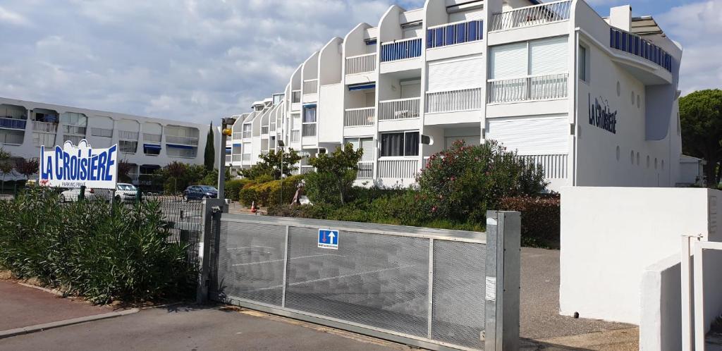 a fence in front of a building with a building at Studio vue port, parking privé, terrasse, clim in Le Grau-du-Roi