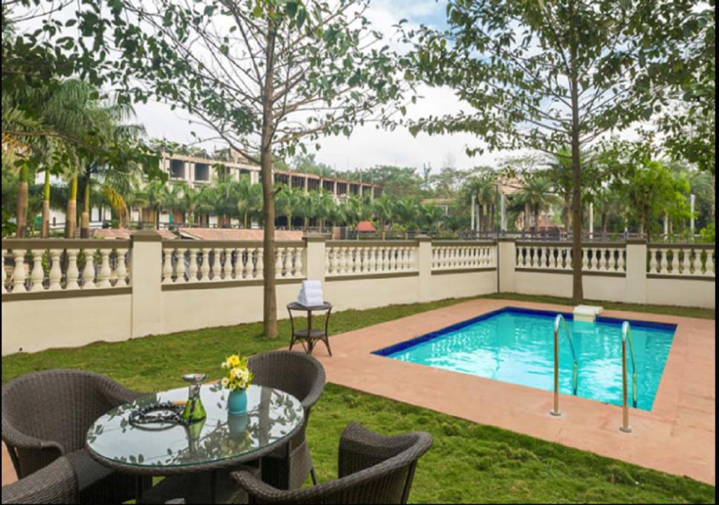 Un patio con una mesa y una piscina. en StayVista's Greenwoods Villa 7 - City-Center Villa with Private Pool, Terrace, Lift & Ping-Pong Table, en Lonavala