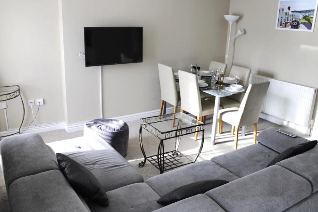 - un salon avec un canapé et une table à manger dans l'établissement The Clifton Holiday Apartment Llandudno Centre, à Llandudno