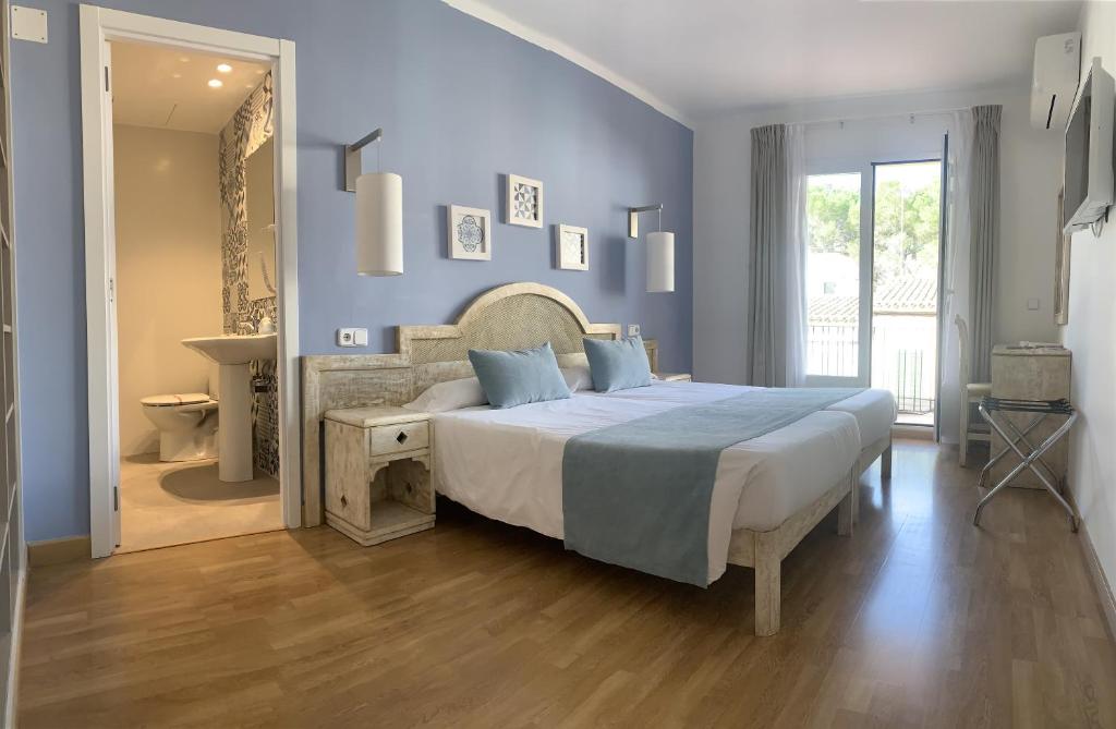 1 dormitorio con 1 cama grande y baño en Hostal HPC Porto Colom, en Portocolom