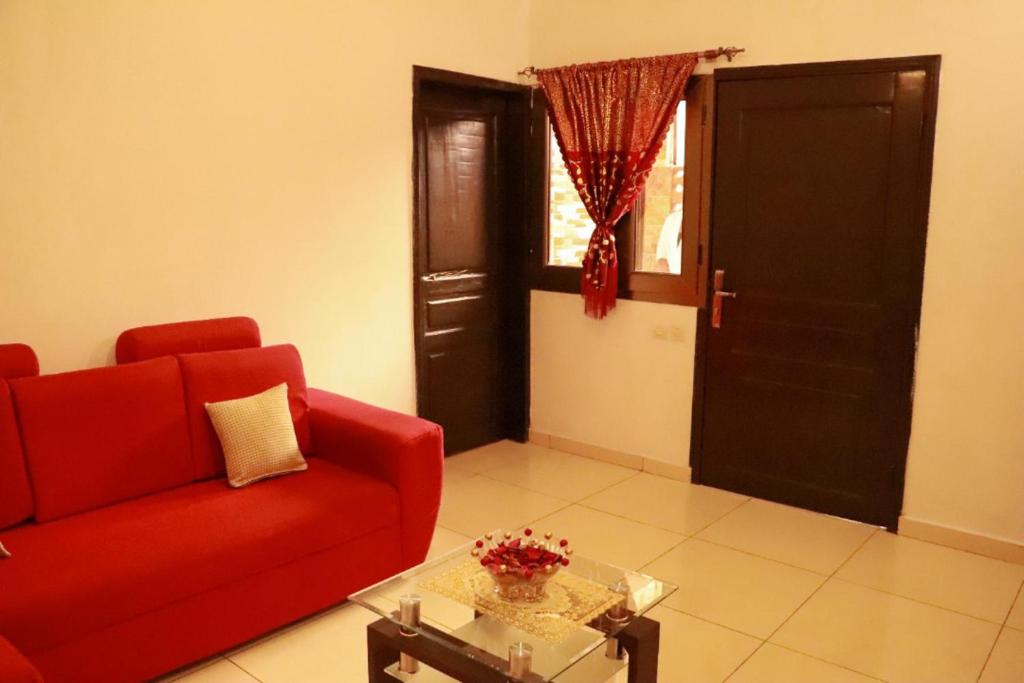 - un salon avec un canapé rouge et une table en verre dans l'établissement Residence Appartements Luxueux -Angre-ABIDJAN, à Cocody