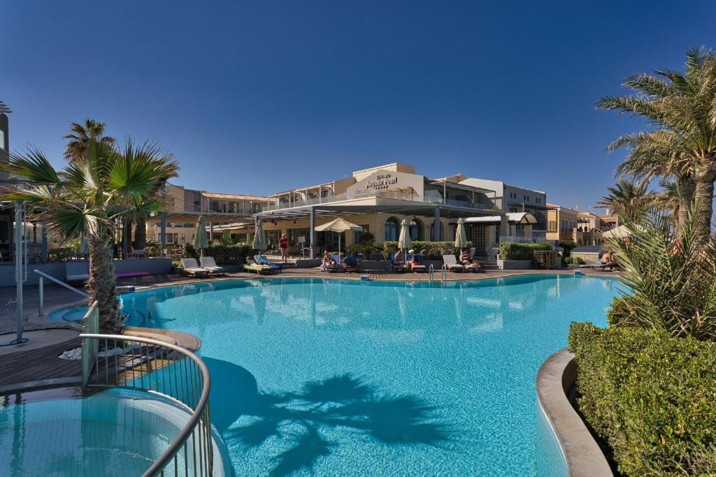 a large swimming pool with palm trees in a resort at Aegean Pearl in Rethymno Town