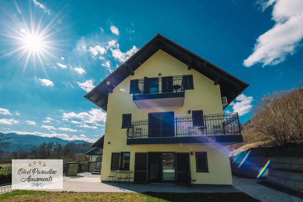 a house with a balcony and the sun in the sky at Hostel Bled Paradise Slovenia in Bled-Rečica