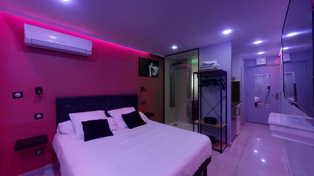 een paarse slaapkamer met een bed en een badkamer bij Village Naturiste Cap d'Agde, Studio Luxe Port Nature 7 in Cap d'Agde