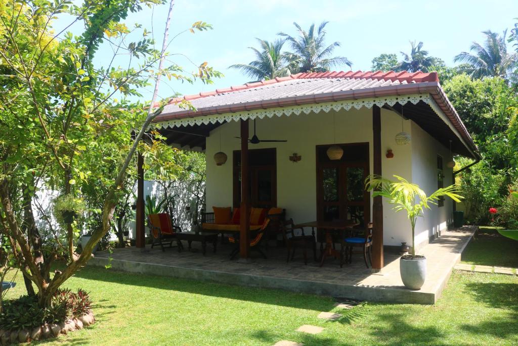 una piccola casa con portico e tavolo e sedie di Lilly House a Unawatuna