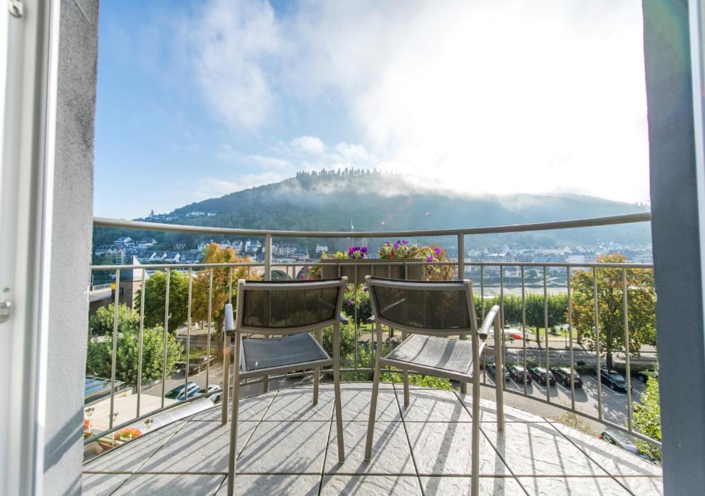 a balcony with two chairs and a view of a mountain at Hotel Cochemer Jung in Cochem