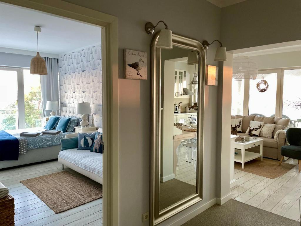sypialnia z lustrem i salon w obiekcie Biały Apartament Hampton w Playa Baltis w mieście Międzyzdroje