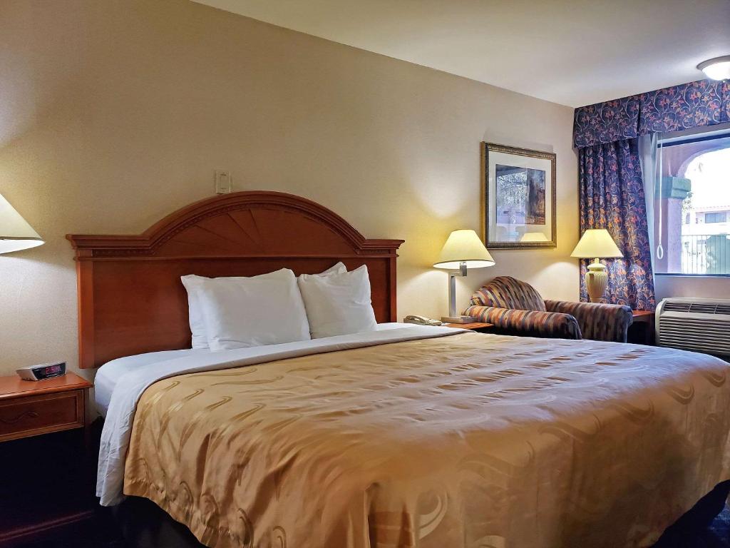 um quarto de hotel com uma cama grande e uma cadeira em Quality Inn Santa Nella on I-5 em Santa Nella