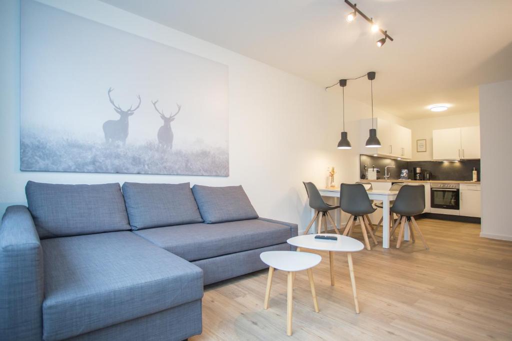 ein Wohnzimmer mit einem blauen Sofa und einer Küche in der Unterkunft Weltringpark 2-T, Winterberg in Winterberg