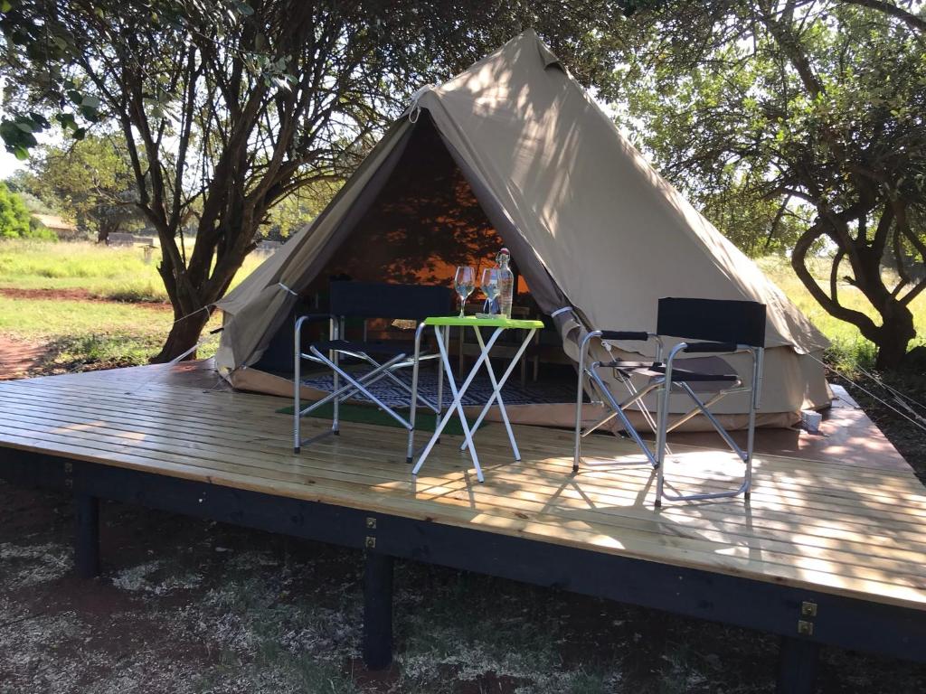 a tent with two chairs and a table on a deck at Hluhluwe Bush Camp Glamping Village in Hluhluwe