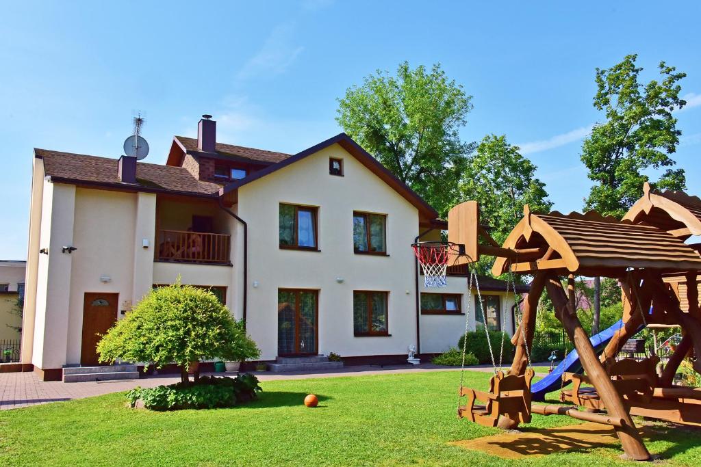 una casa con un parque infantil delante de ella en Žemyna Apartmentai, en Druskininkai