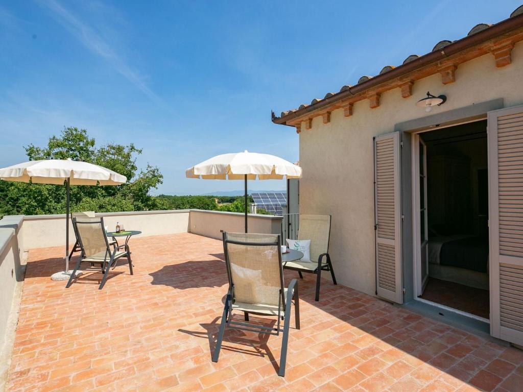 patio z krzesłami i parasolami na ceglanym patio w obiekcie Belvilla by OYO Villa Severina w mieście Cortona