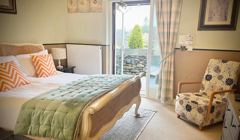 a bedroom with a bed and a chair and a window at The Brown Horse Inn in Winster