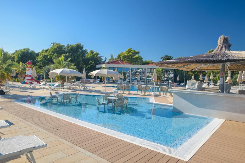 - une piscine avec des tables, des chaises et des parasols dans l'établissement Camping Stobreč Split, à Split