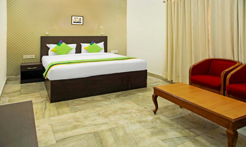 Pokój hotelowy z łóżkiem i czerwonym krzesłem w obiekcie Treebo Trend Kumily Gate Thekkady w mieście Thekkady