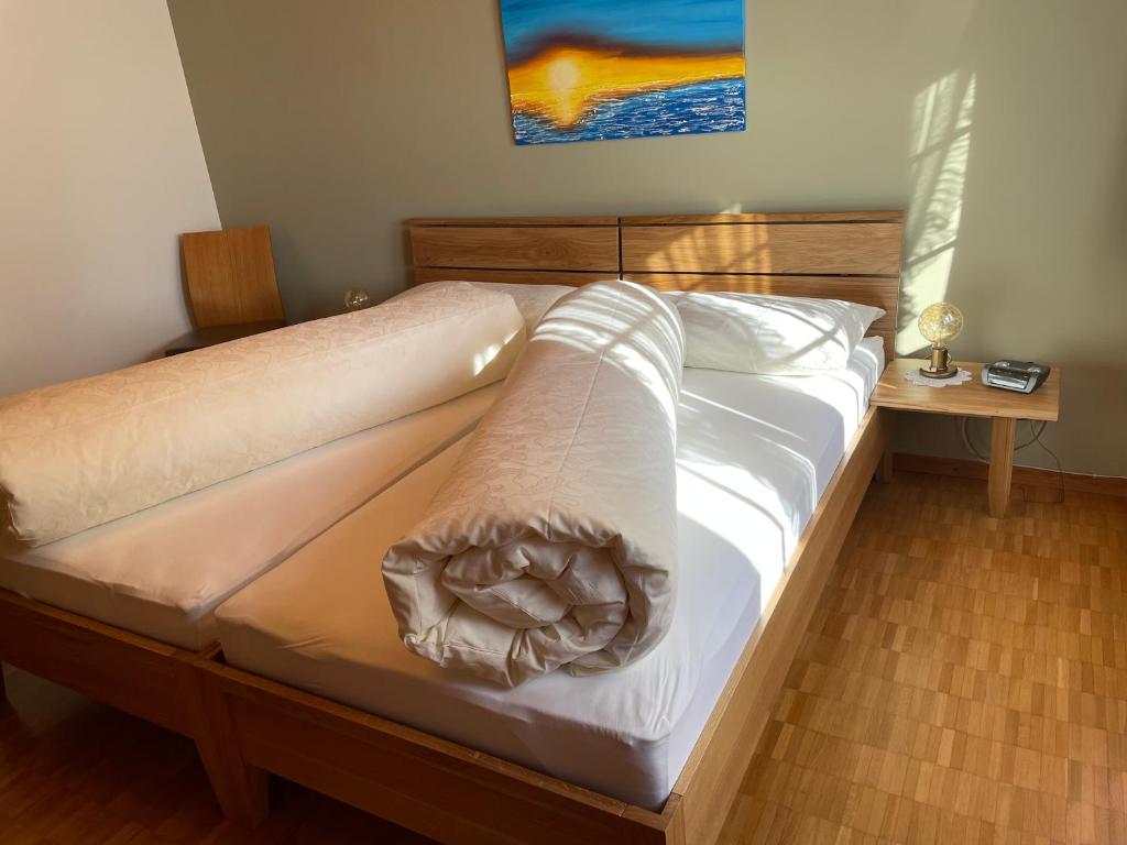 a bed with white sheets and a blanket on it at Hotel Pension Im Dorf in Zuzwil