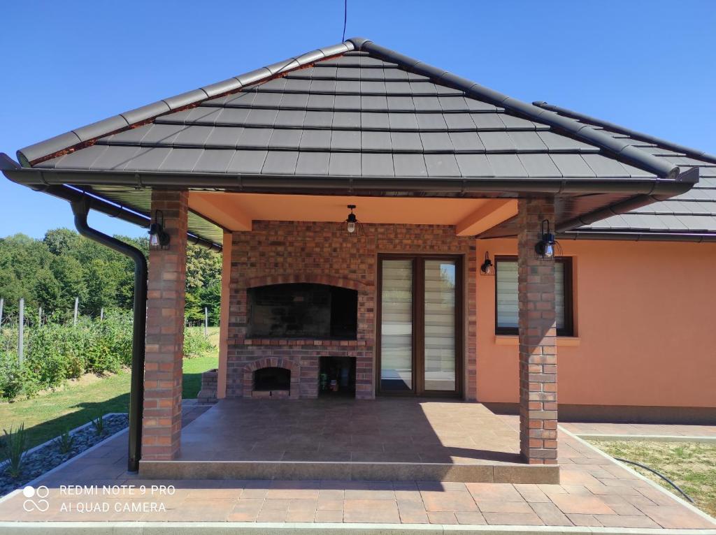 a pavilion with a brick fireplace in front of a house at Apartman A&E in Živinice