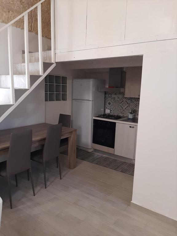 eine Küche mit weißen Schränken sowie einem Holztisch und Stühlen in der Unterkunft Casa di Carmine 2 in Galatina
