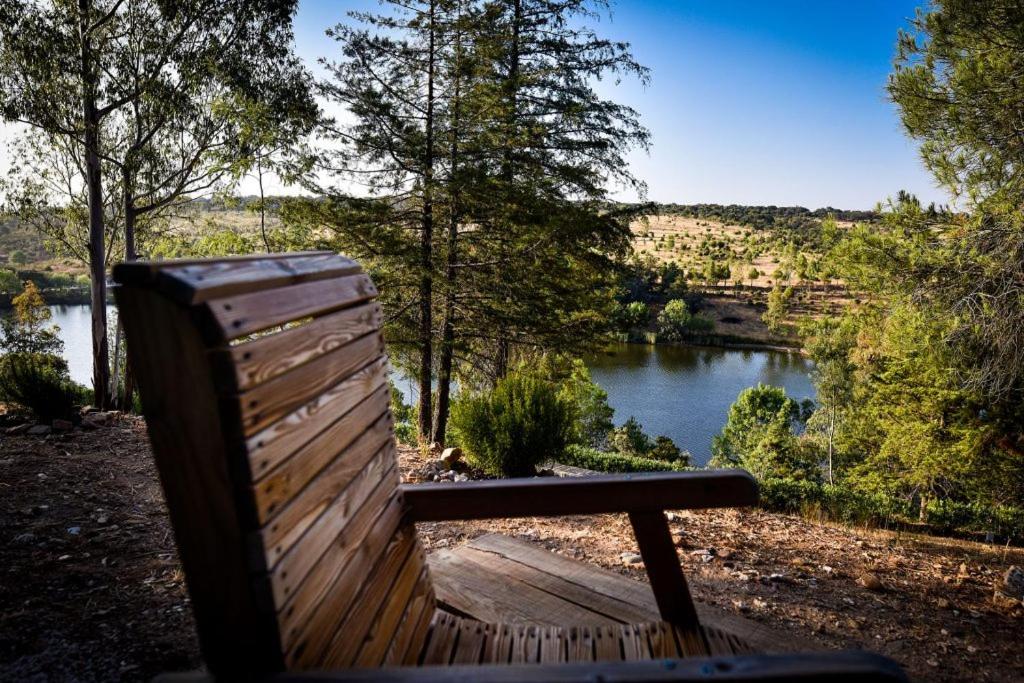 a wooden bench sitting in front of a lake at Herdade Clube Tiro Monfortinho in Monfortinho