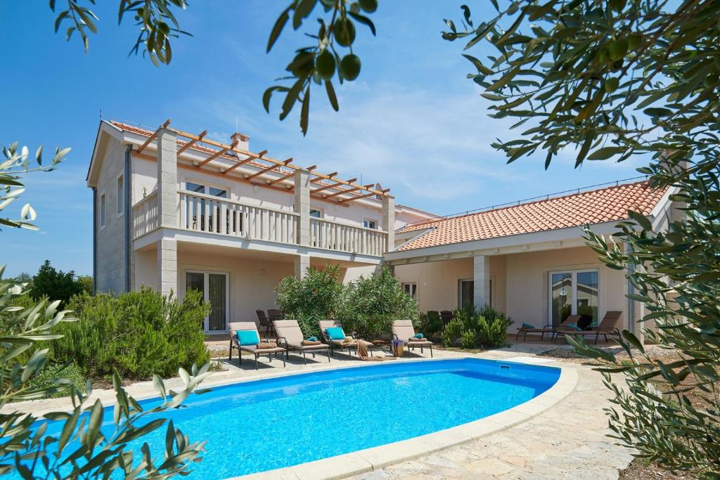 een villa met een zwembad en een huis bij Hvaretta Villas in Stari Grad