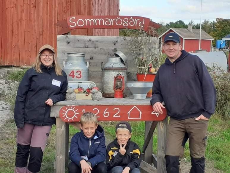 een man en een vrouw en twee kinderen die onder een bord zitten bij Sommarö Stugor in Föglö