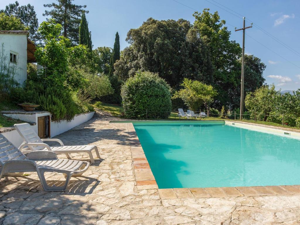 a swimming pool with two lounge chairs next to a house at Belvilla by OYO La Cantina in Umbertide