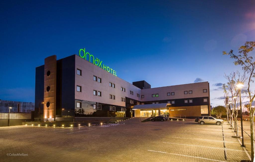 a building with a parking lot in front of it at DMax Hotel in Marília