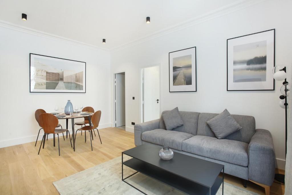 ein Wohnzimmer mit einem Sofa und einem Tisch in der Unterkunft Apartment Palais Royal by Studio prestige in Paris