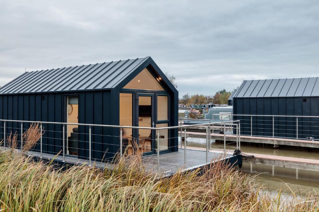 Ein schwarzes Gebäude auf einem Dock neben einem Jachthafen. in der Unterkunft Tattenhall Marina Floating Pods in Hargrave