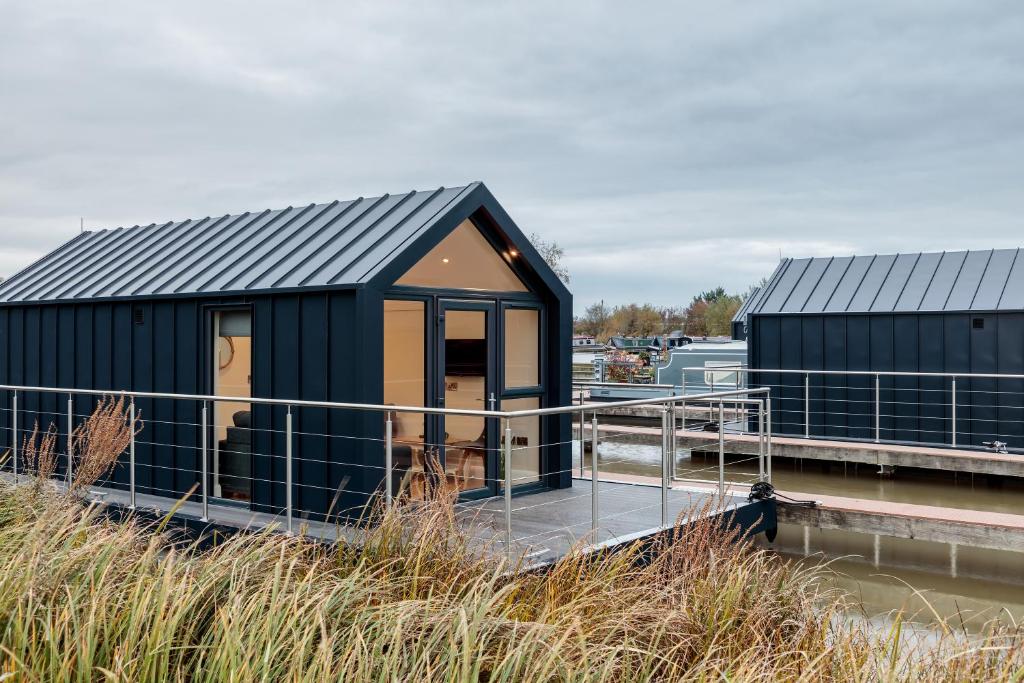 a black building on a dock next to a marina at Tattenhall Marina Floating Pods in Hargrave