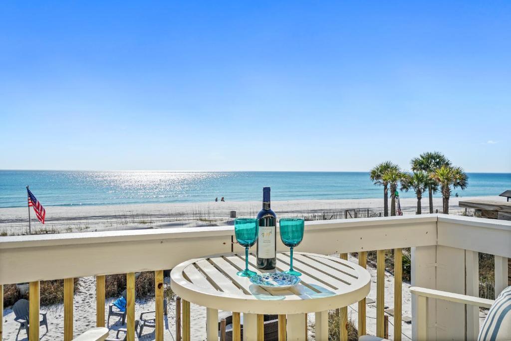 una mesa con 2 copas de vino en un balcón con vistas a la playa en Beachside West Townhome, en Panama City Beach