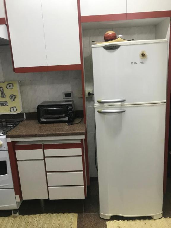 a kitchen with a white refrigerator and a microwave at Aconchegante e prático in Campinas