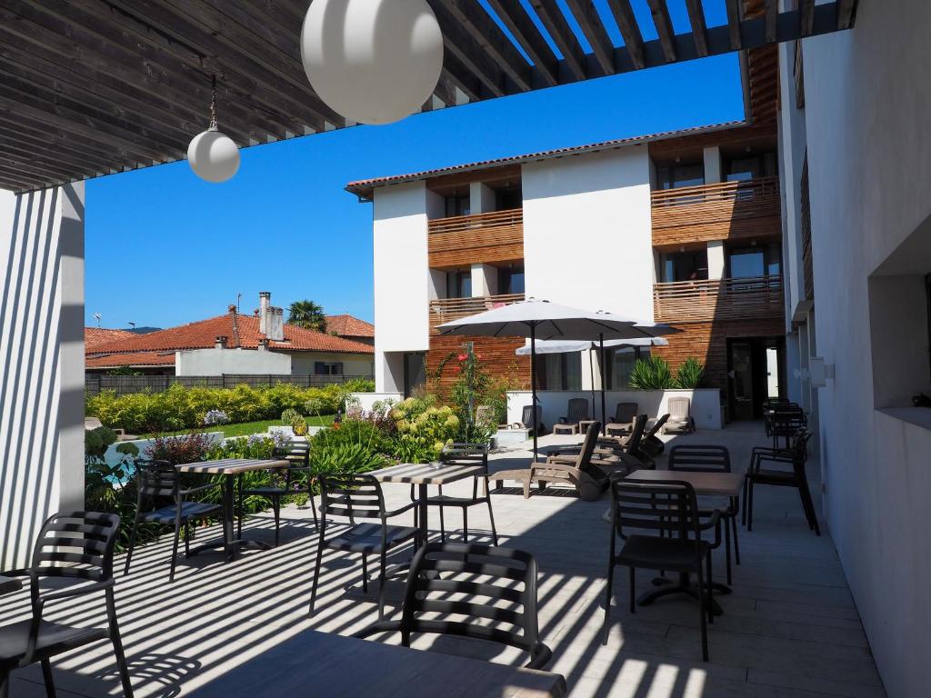 un patio avec tables, chaises et un parasol dans l'établissement Hotel Restaurant Santiago, à Hendaye
