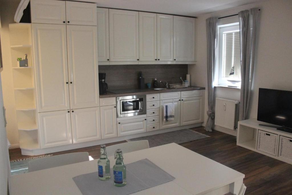 een keuken met witte kasten en een tafel met drankjes erop bij Appartement 660 Erik in Flensburg