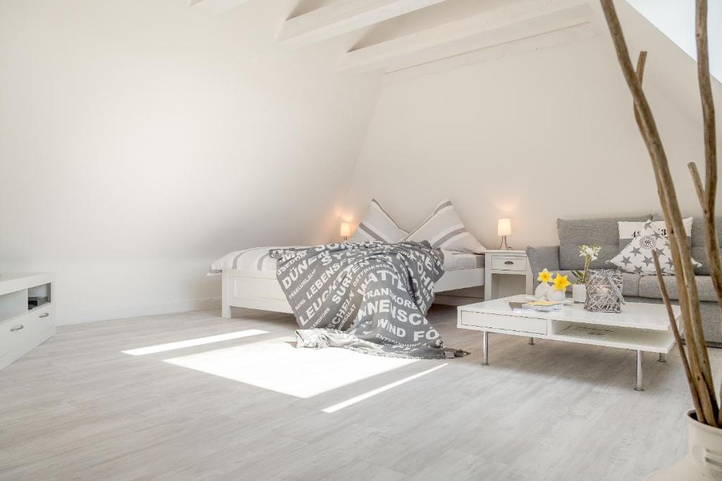 a white bedroom with a bed and a table at Ferienwohnung - Tessa in Tinnum