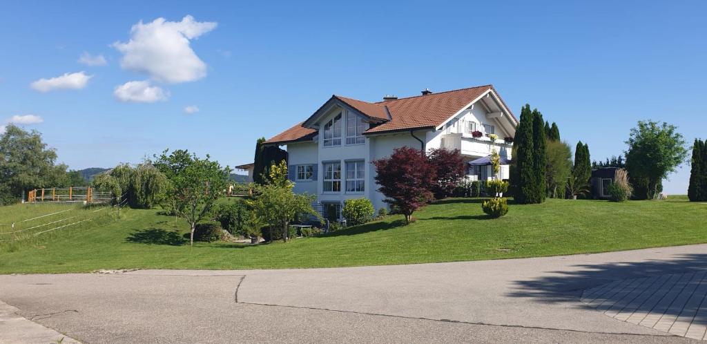 a large white house on a hill with a yard at Ferienwohnung Hensel am Herzmannser See in Waltenhofen